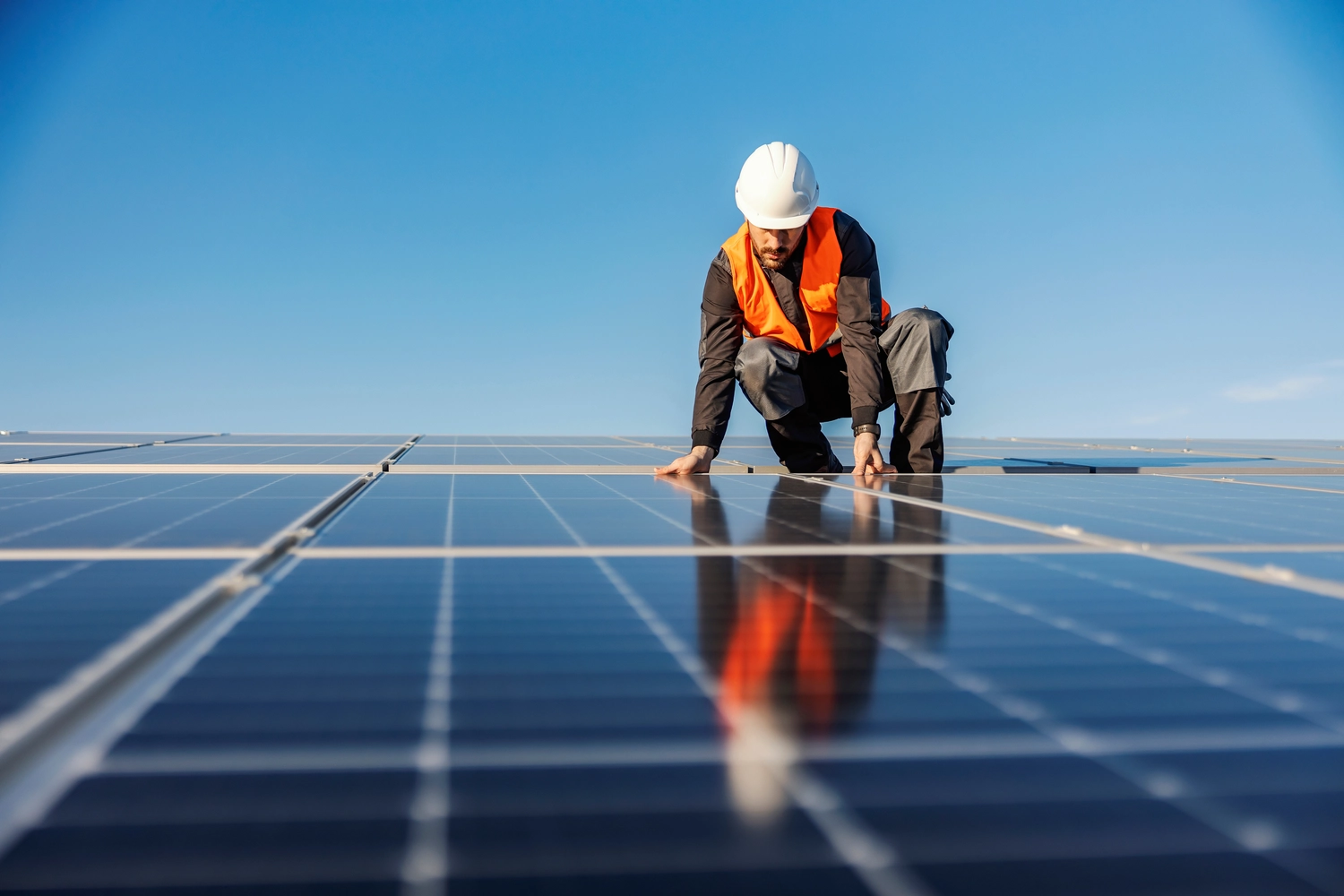 Ein Handwerker installiert Solarmodule auf dem Dach.